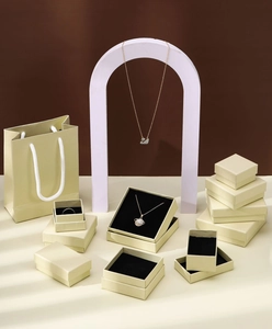 Detail shot of champagne paper jewelry boxes with matching gift bags and black velvet foam inserts