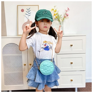 Detail of mint green heart-quilted round chain bag with children summer outfit