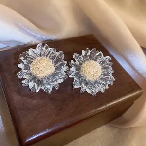 Elegant clear sunflower stud earrings with golden centers on a dark wood box
