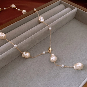 Detail of irregular baroque pearls and gold-plated chain on a velvet jewelry display