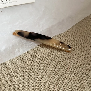 Dettaglio del fermaglio in acrilico tartarugato con base in metallo dorato inciso