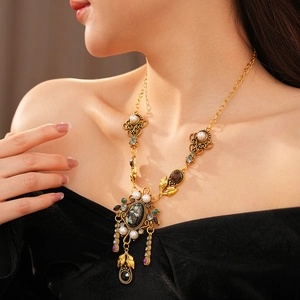 Détail d'un collier baroque vintage avec feuilles en or antique et perles blanches