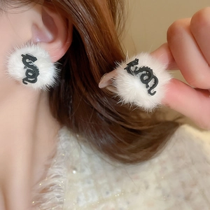 Detail view of white plush heart earrings with black dragon embossed pattern