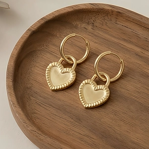 Detail of heart hoop earrings with cream enamel finish and sunburst gold texture
