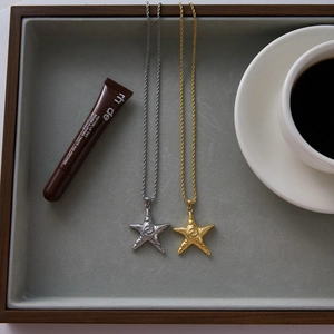 Luxurious gold and silver starfish pendant necklaces on a grey display tray