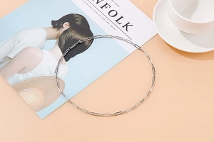 Collier à maillons trombone argenté sur magazine avec décor de tasse à café