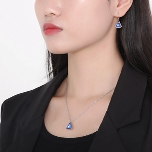 Close-up of model wearing blue triangular crystal necklace and earrings in silver setting