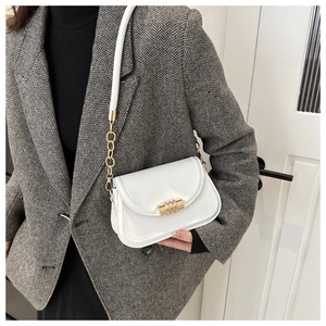 Detail of white glossy saddle bag with a golden cylindrical twist lock and chain strap