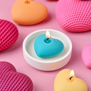 Candele a cuore a nido d'ape galleggianti colorate in un piatto di ceramica