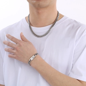 Close-up of polished silver double-weave Cuban chain necklace and bracelet set for men