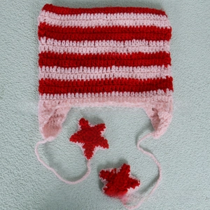 Detail of handmade crochet striped hat featuring pink and red stripes with star charms