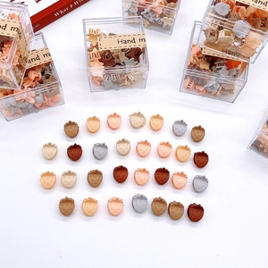 Macro view of assorted mini resin strawberry hair clips in a clear gift box and scattered