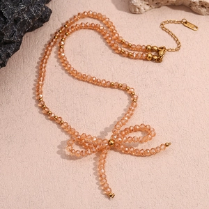 Close-up of champagne faceted crystal beaded necklace with a golden bow pendant