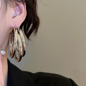 Close-up of silver layered hoop earrings on a model showing polished metal texture