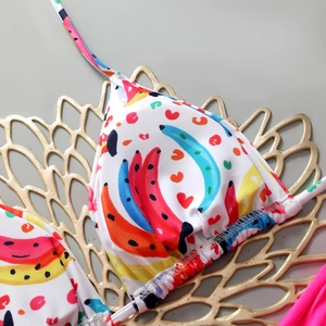 Macro detail of white bikini top with colorful banana and heart print and halter straps