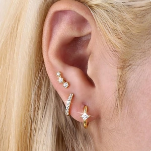 Detail of gold ear cuff and stud earrings set with crystal stones on female ear