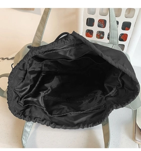 Interior view of black drawstring tote showing zipper pocket and lining detail
