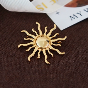 Macro shot of gold sunburst brooch pinned on brown knit sweater with a polished finish
