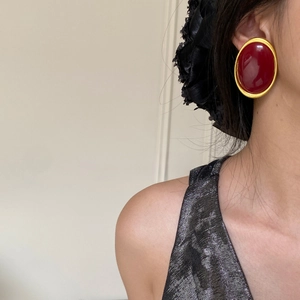 Close-up of vintage red oval earrings with gold trim on model for a stylish retro look