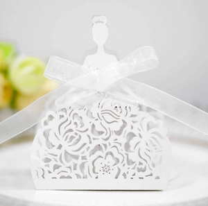 Detail of laser-cut white bridal gown candy box with floral patterns and satin ribbon