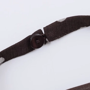 Detailed close-up of dark brown polka dot fabric featuring a round button and buckle clasp
