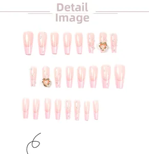 Detail of pink French press-on nails featuring white pearls and heart-shaped rhinestones