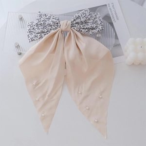 Close-up of floral bow hair clip with beige ribbons and delicate white pearls detail