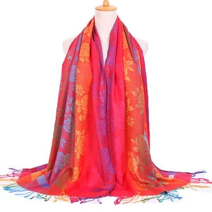 Detail of colorful jacquard scarf with rose patterns and fringe trim on a mannequin