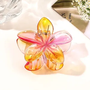 Macro detail of gradient yellow and pink plumeria hair claw clip with iridescent finish