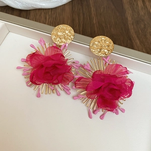 Detailed view of oversized red chiffon flower earrings with gold metallic accents