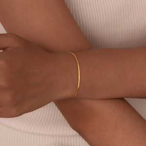 Elegant gold-plated snake bone chain bracelet worn by a female model on a white background