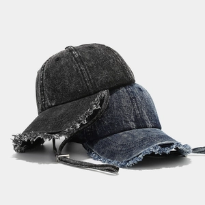 Dettaglio del cappello da baseball in denim con bordi sfilacciati e cordino antivento
