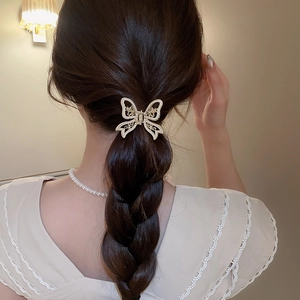 Detail showing an elegant hollow butterfly hair claw with pearls on a model's dark hair