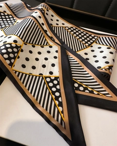 Detail of soft silk scarf with black white polka dots and gold geometric patterns