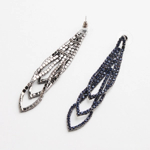 Detailed macro view of geometric leaf tassel earrings with sparkling rhinestones set on white