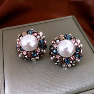 Vintage round pearl earrings with colorful gemstone halo on grey jewelry box