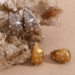 Macro de boucles d'oreilles goutte dorées 18K avec métal brossé et incrustations de perles