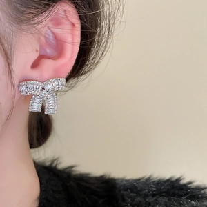 Primo piano di orecchini a fiocco scintillanti con zirconi indossati da una modella