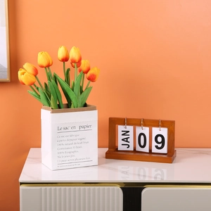 Minimalist wooden perpetual flip calendar with elegant orange tulips on a marble desk