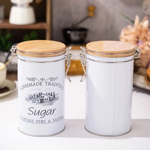 Detail of white tinplate sugar canisters with airtight bamboo lids and metal buckles