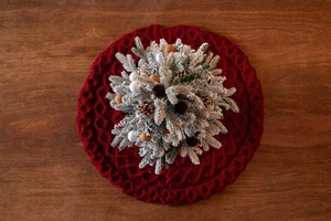 Détail de la jupe de sapin de Noël rouge en tricot torsadé avec mini sapin et pommes de pin