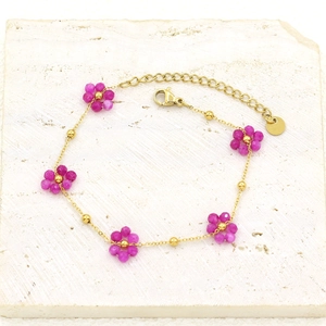 Detail of gold-plated stainless steel bracelet with magenta stone flower charms