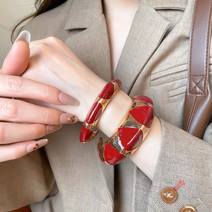 Detail of red enamel and gold-plated geometric open cuff bracelet on model's wrist
