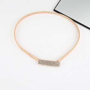 Detail of a thin gold elastic spring belt featuring a rectangular rhinestone buckle