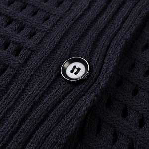 Macro shot of navy knit fabric texture featuring openwork patterns and a black button