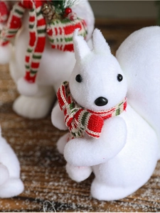 Close-up of a white flocked Christmas squirrel ornament with a red and green striped scarf