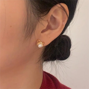 Close-up of bow knot pearl stud earrings with crystals on gold plated 925 silver