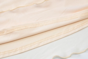 Detail of fine overlock stitching on double-layer mesh and beige fabric for the skirt