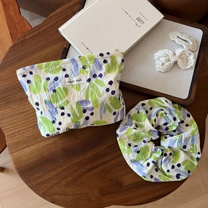 Detailed set featuring a leaf print drawstring pouch and matching hair scrunchie on wood