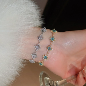 Close-up of geometric gold bracelet with square blue zircon and sparkling diamond accents